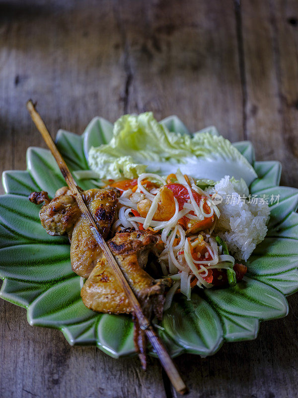 Som Tam Tai,一个受欢迎的和最喜欢的泰国菜菜的年轻切木瓜、辣椒、西红柿、棕榈糖和虾米,配上烤鸡翅和糯米。